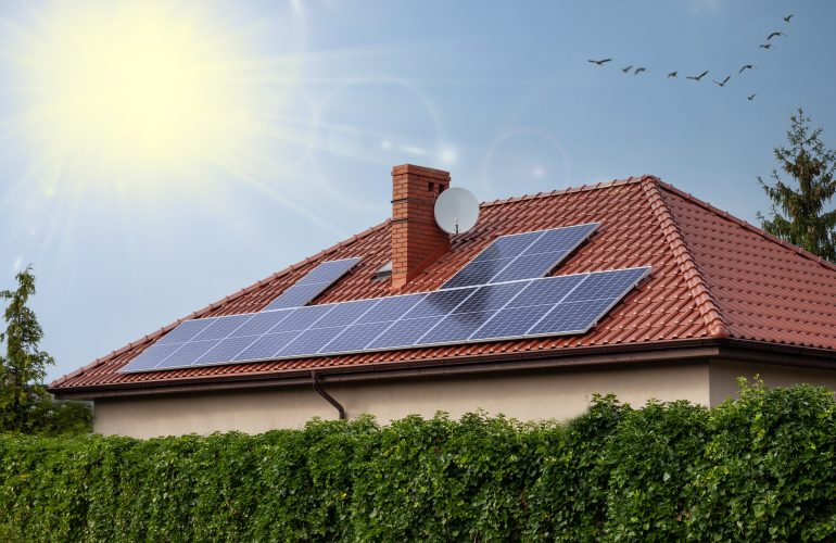 Renewable clean green energy saving efficient photovoltaic solar panels on house roof over blue sky.