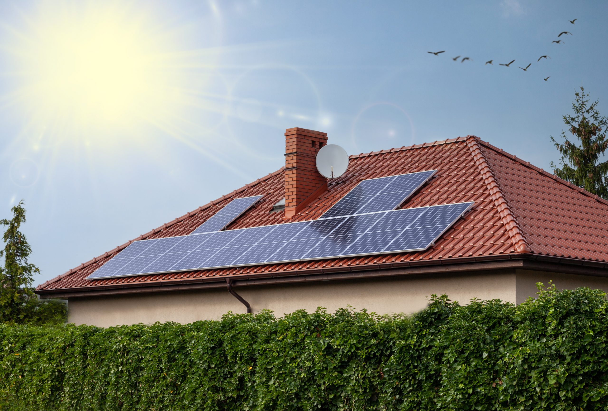Renewable clean green energy saving efficient photovoltaic solar panels on house roof over blue sky.